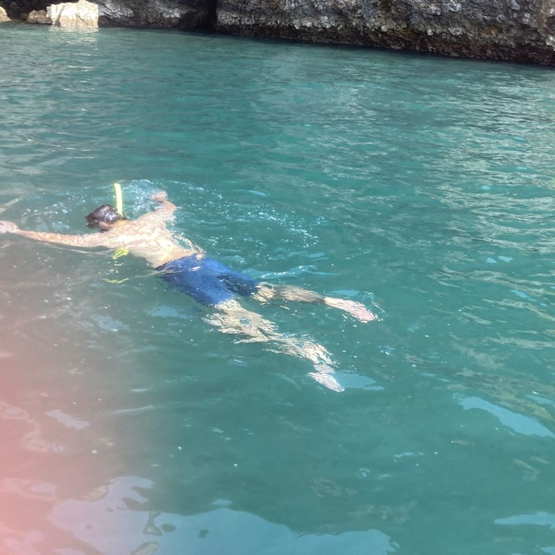 Faraz snorkelling in turquoise water beside a limestone cliff in Thailand